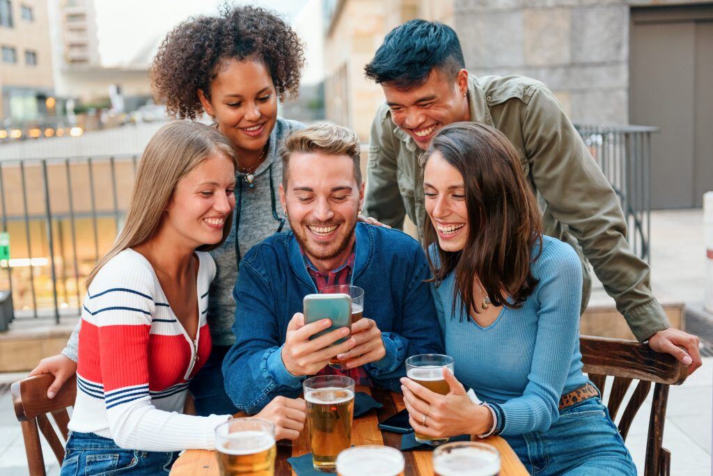 Eine Gruppe junger Menschen sieht sich Social Media Videos an - Gerade für Unternehmen ist die Reichweite sehr lukrativ