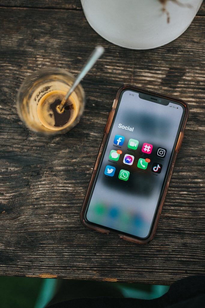 Ein Handy auf einem Tisch mit Social Media Icons - Social Media Marketing funktioniert mit Video Content besonders gut