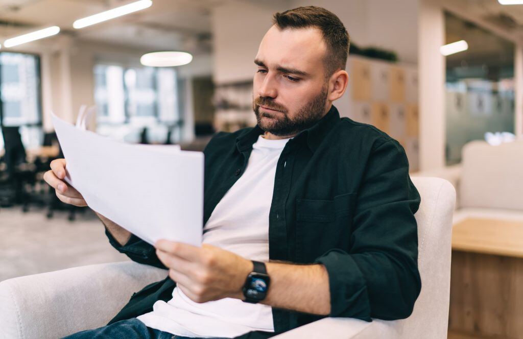 Ein Mann liest Papierberichte im Büro - im Rahmen des Coachings von Führungskräften und dem Business Coaching für Marketing bei uns in Reutlingen achten wir darauf, dass sie Lead Management und Sales Tracking Systeme implementieren.